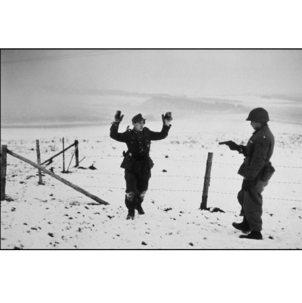 Un soldat américain et un prisonnier de guerre allemand durant la bataille des Ardennes, près de Bastogne, Belgique, décembre 1944. ©Robert Capa @International Center of Photography/Magnum Photos